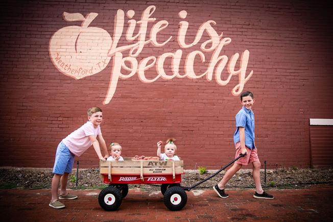 Four children play in front of a mural reading 