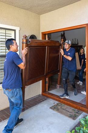 Two men wearing Caring Transitions t-shirts moving furniture.